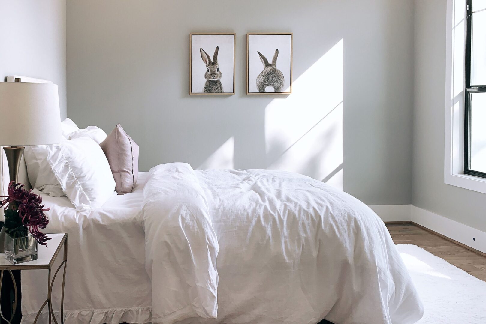 A white bed in a bedroom with two framed pictures.