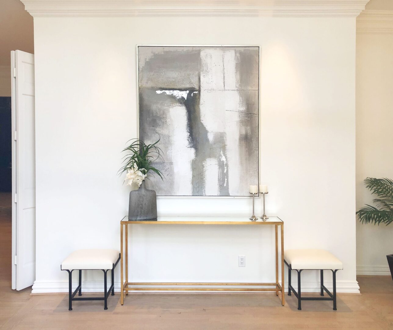An entryway with a gold console table and a painting on the wall.